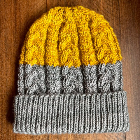 Gray and yellow knitted hat on a wooden surface
